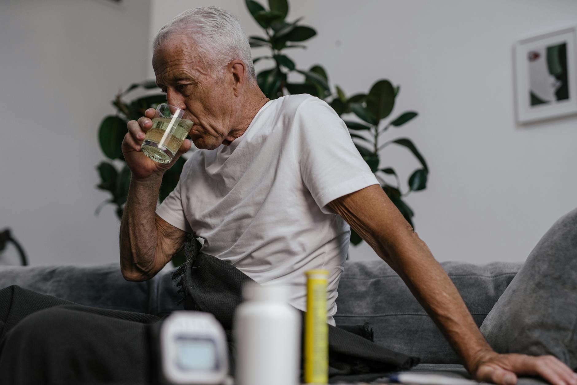 elderly man in white shirt drinking from clear drinking glass